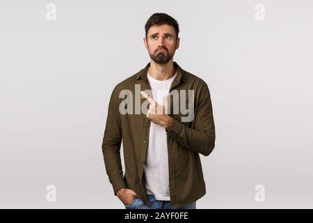 Man regret missed good opportunity feeling sad and miserable. Upset young bearded guy pulling gloomy face, frowning and look dep Stock Photo