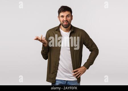 Man having complain, arguing with business partner. Displeased and annoyed, aggressive bearded man raise one hand frustrated and Stock Photo
