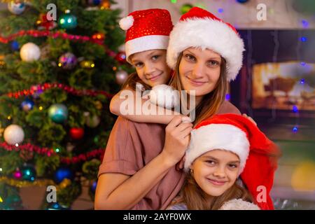 Mother and two daughters at the Christmas tree Stock Photo