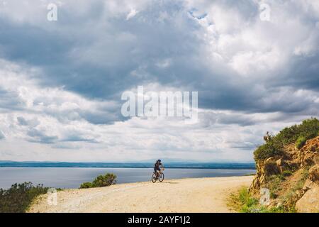 young guy riding a mountain bike on a bicycle route in Spain. Athlete on a mountain bike rides off-road against the background o Stock Photo