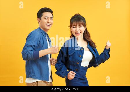 Dance Like Nobody's Watching. Emotional guy and girl having fun over yellow background, copy space Stock Photo