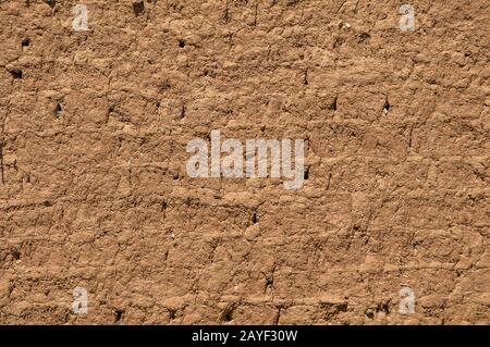 Adobe clay weathered wall of rural vintage country house closeup as clay background Stock Photo