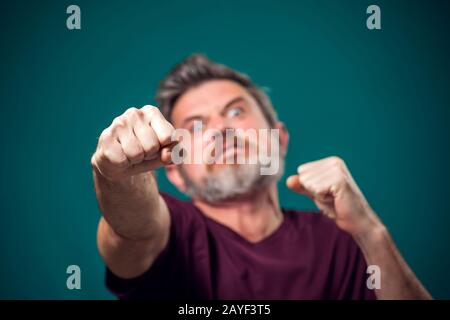 A portrait of bearded angry man in red t-shirt showing fist at camera. People and emotions concept Stock Photo