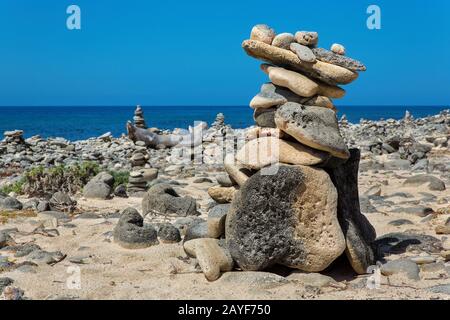 Stack of pebbles on beach of Bonaire with blue sea Stock Photo
