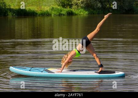 Young caucasian woman exercises yoga on SUP Stock Photo