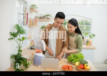 Portrait of a pretty young couple cooking together according to a recipe on a tablet computer Stock Photo