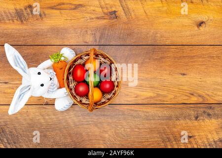 Seven colourful Easter eggs in the basket and Easter bunny wooden background Stock Photo