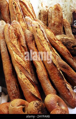 Loafs of freshly baked French baguette bread stacked leaning against a stone wall Stock Photo