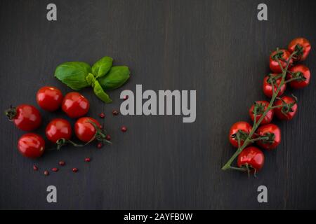 Fresh grape tomatoes with pepper for use as cooking ingredients on wooden background Stock Photo