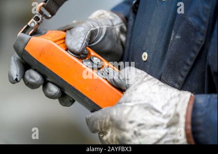 Male hand push remote control switch for overhead crane in the factory, close-up. Electrical control panel of the crane and other lifting equipment in laborer hand . Stock Photo