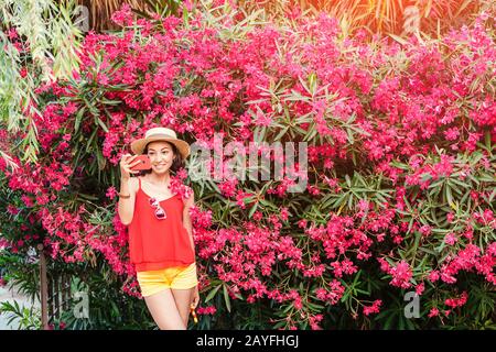 Beautiful stylish asian woman making selfie in blossom magnolia garden Stock Photo