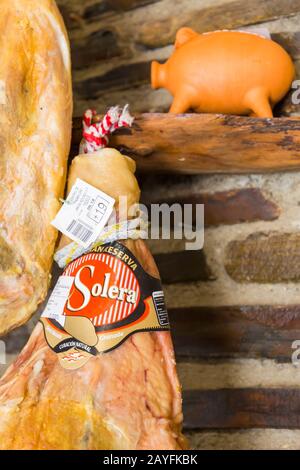 ham and piggy bank for sale in shop at La Solera de la Alpujarra, Trevelez (one of the highest villages in Spain), Andalucia, Spain in February Stock Photo