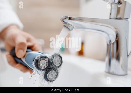 Man cleans electric razor after shaving Stock Photo