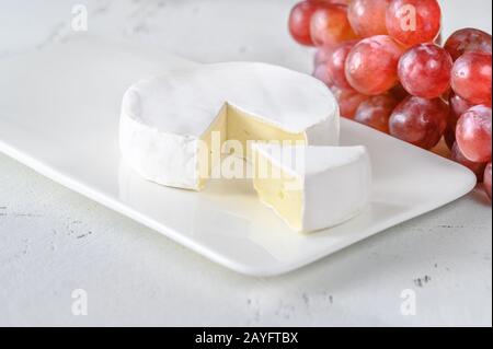 Camembert with bunch of grapes on the serving plate Stock Photo