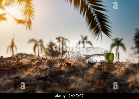 Close up clear plastic bottle water drink with a green cap on the road in the park at blurred background, Trash that is left outside the bin, litter o Stock Photo