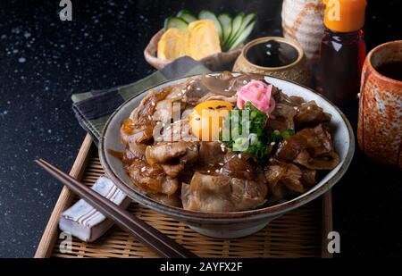 Japanese style rice with slice pork and soya sauce simmer topping with raw egg and onion green. Stock Photo