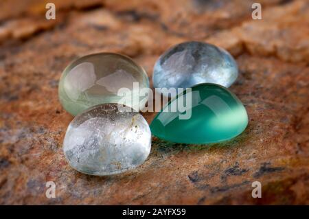 Round cut quartz and emerald mineral gemstones with stone background. Stock Photo