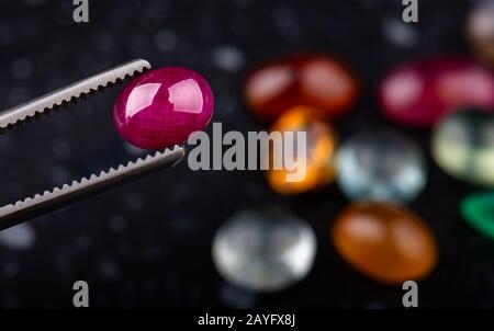 Round cut ruby mineral gemstone with dark stones background. Stock Photo