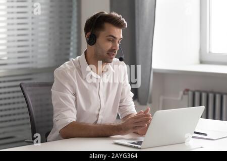 Busy male employee in headset talk on video call Stock Photo