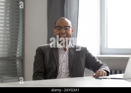 Overjoyed male worker laugh talking with colleague in office Stock Photo