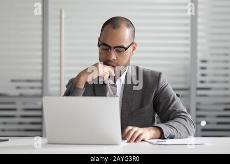 Pensive male employee look at laptop think analyzing problem Stock Photo