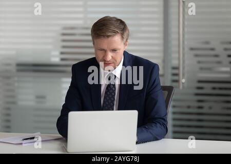 Focused male CEO busy using laptop at workplace Stock Photo