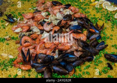 A large paella dish cooking fresh seafood in a Spanish market on a marketplace stall with fresh ingredients Stock Photo