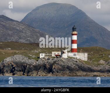 The tall, red and white striped Eilean Glas lighthouse, Scalpay, from the sea, with the hills of Harris behind, Western Isles, Scotland Stock Photo