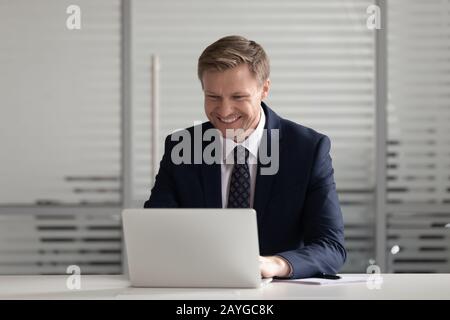 Smiling businessman busy working on laptop in office Stock Photo