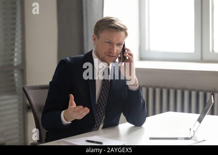 Serious male ceo having phone conversation with business client Stock Photo