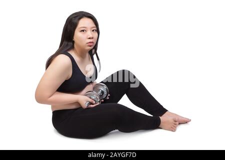 beautiful chubby fat woman lift dumbbell sitting on ground doubt about exercise weight training Stock Photo