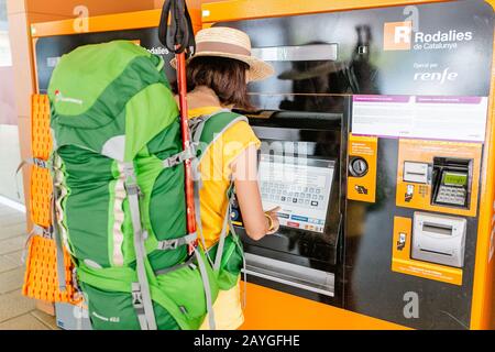 27 JULY 2018, VIC, SPAIN: Traveler woman buying a ticket at a publice transport ticket vending machine Renfe at the train station Stock Photo