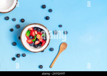 Healthy breakfast concept. Coconut bowl with fresh berries on blue background. Top view with copy space Stock Photo
