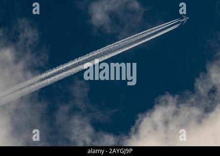 Emirates A380 leaving contrails across a dark blue cloudy sky. Stock Photo