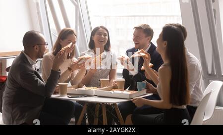 Happy diverse colleagues enjoy pizza having fun at lunch break Stock Photo