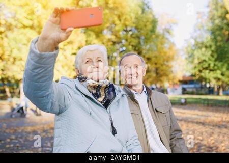 Happy Senior couple taking selfie on smartphone in park Stock Photo