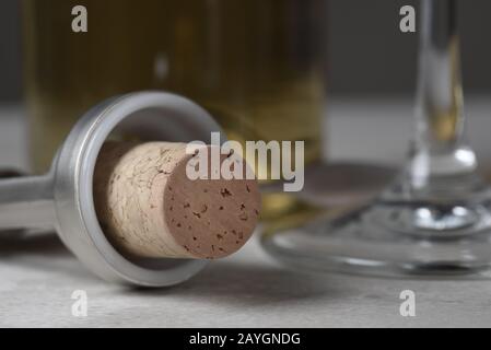 Closeuup of a wine cork in wing style corkscrew with glass and bottle in background.  Shallow depth of field. Stock Photo