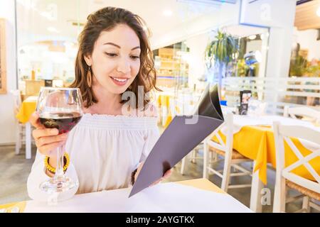 Woman drinking wine and reading menu in restaurant Stock Photo