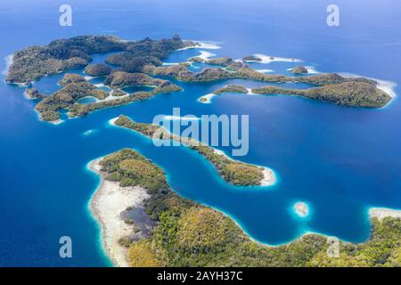 Forest-covered limestone islands rise from the seascape in Raja Ampat, Indonesia. This remote region is known for its great marine biodiversity. Stock Photo