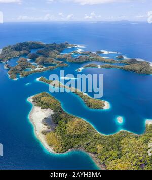 Forest-covered limestone islands rise from the seascape in Raja Ampat, Indonesia. This remote region is known for its great marine biodiversity. Stock Photo