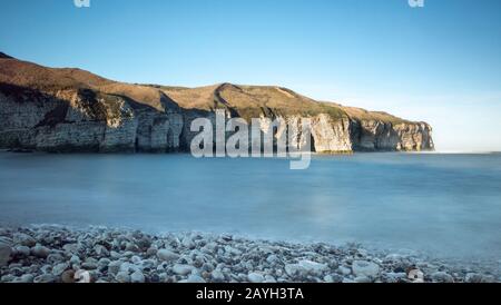 The Flamborough cliffs at North Landing in East Yorkshire, with a stony beach in the foreground Stock Photo