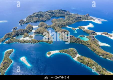 Forest-covered limestone islands rise from the seascape in Raja Ampat, Indonesia. This remote region is known for its great marine biodiversity. Stock Photo