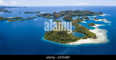 Forest-covered limestone islands rise from the seascape in Raja Ampat, Indonesia. This remote region is known for its great marine biodiversity. Stock Photo