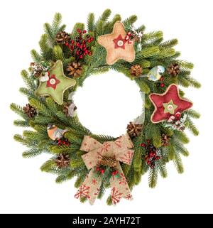 Traditional rustic Christmas wreath of green spruce branches decorated with red holly berries, spruce cones, star baubles and a bow, with two sitting Stock Photo