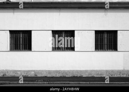 Old-fashioned factory shed with windows gratings and chimney in the southern suburbs of Milan, Italy Stock Photo