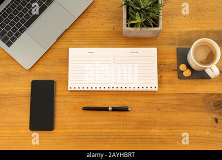 Table Top desk view with pencil a plant, coffee, workspace, mobile display and laptop business, calendar Stock Photo