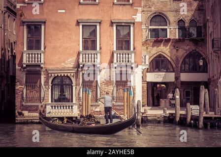 Venice, Italy - May 18, 2017: The gondola with tourists floats along the canal. Gondola is the most attractive tourist transport in Venice. Stock Photo
