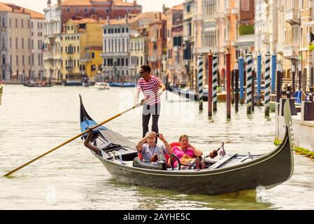 Venice, Italy - May 18, 2017: The gondola with tourists floats along the Grand Canal. Gondola is the most attractive tourist transport in Venice. Stock Photo