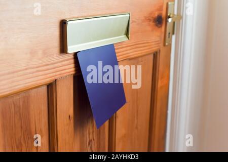 Blank leaflet or flyer being posted through a letter box unwanted junk mail Stock Photo