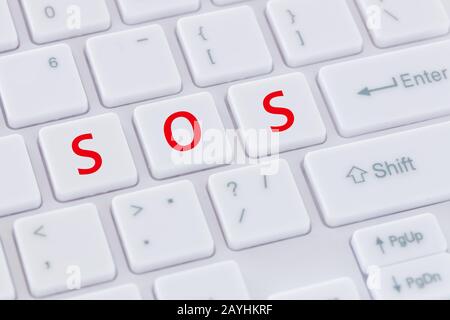 white computer keyboard with red keys arranged in the words "SOS. Stock Photo